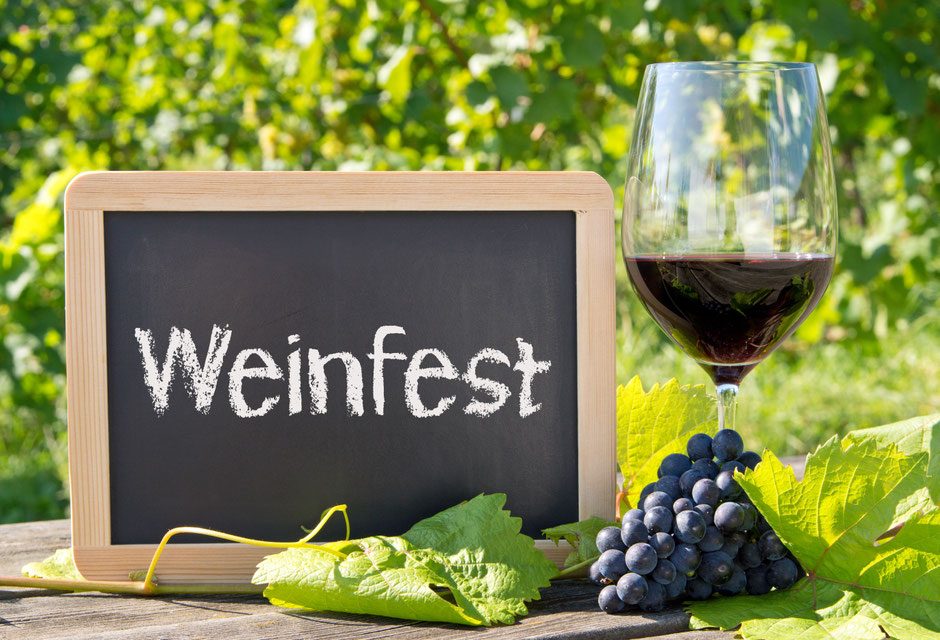 Weinglas und Tafel mit der Aufschrift Weinfest in den Reben