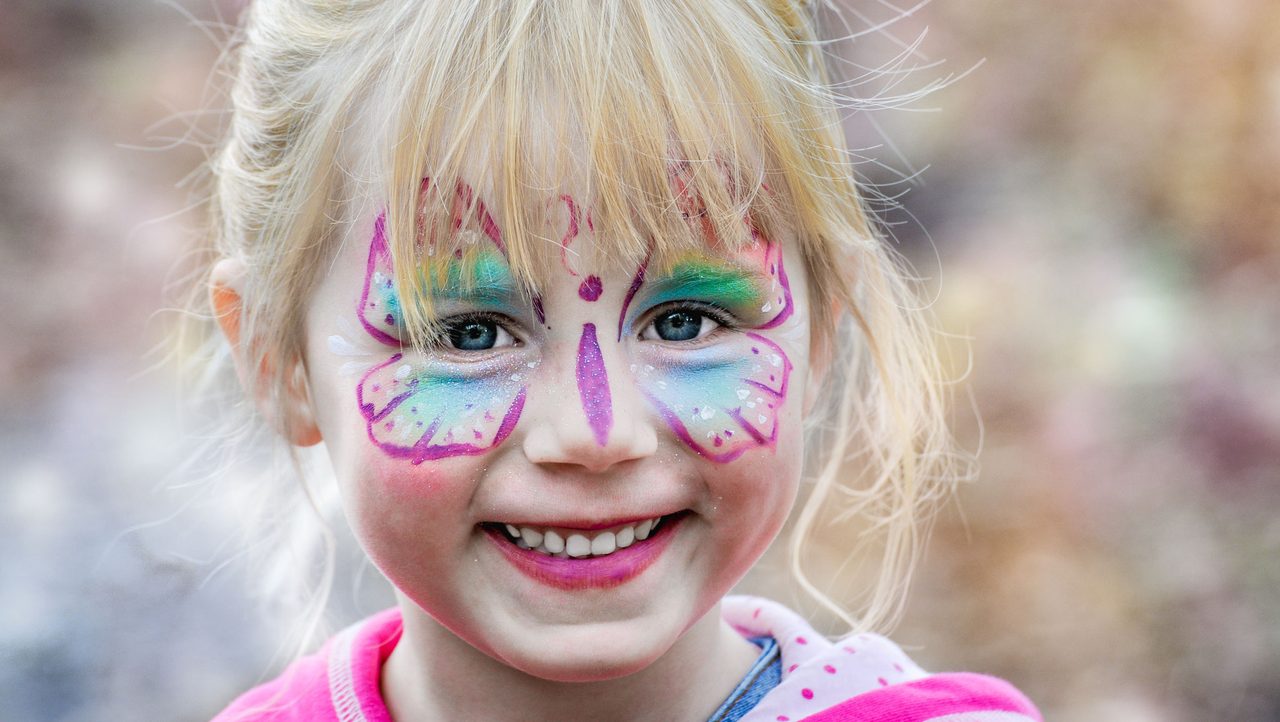 Kind mit Schmetterling-Kinderschminke lacht